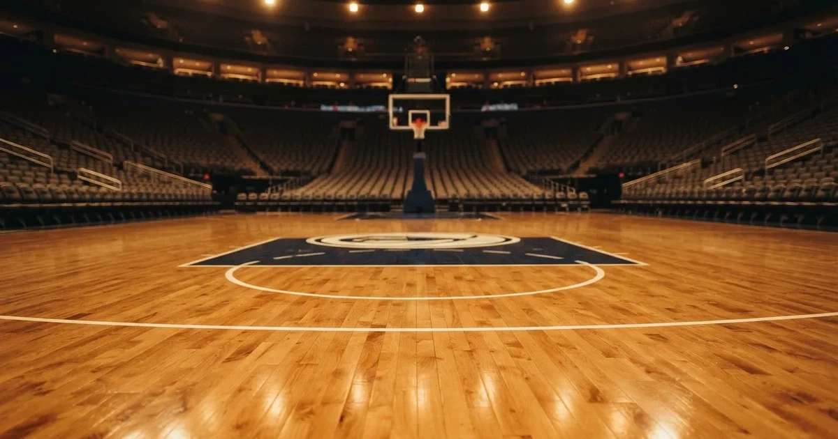 Eine leere Basketballhalle mit glänzendem Parkett und einem Korb im Hintergrund, Licht von Deckenstrahlern spiegelt sich im Boden.