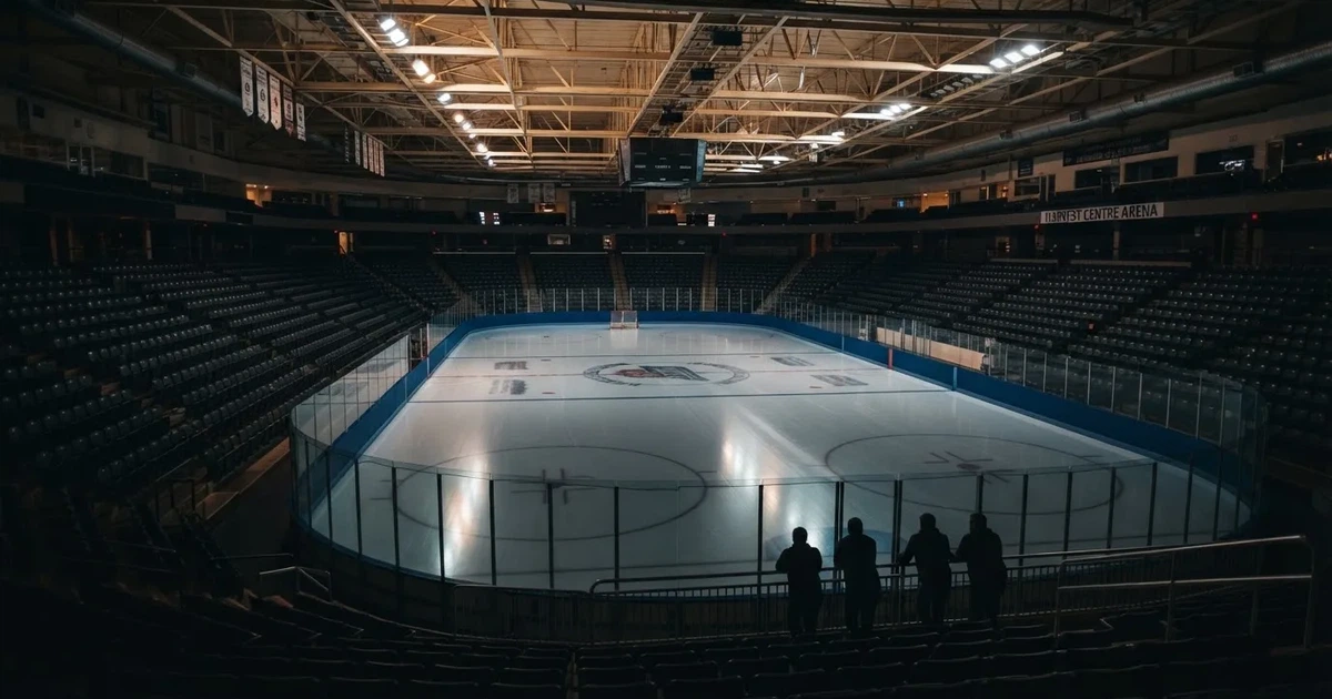 Eine Eishockeyhalle von der Tribüne aus gesehen, spiegelglatte Eisfläche, Banden ohne Schriftzüge, helles Flutlicht.